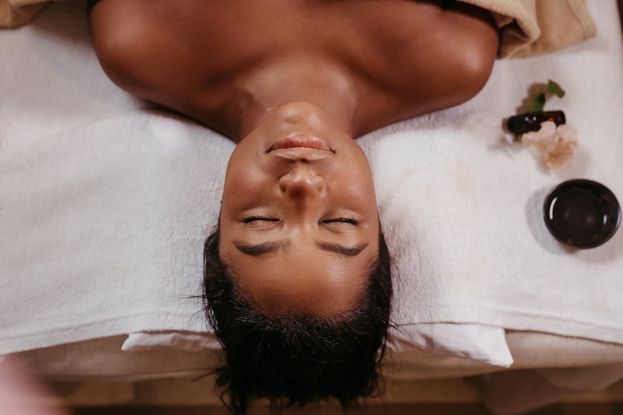 creative-02 A woman enjoying a peaceful spa treatment, lying topless with eyes closed on a white towel.